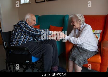 Ein älteres Paar in den Achtzigern, das nach einer mehrwöchigen Trennung aufgrund der Coronavirus-Pandemie, Hampshire, England, wieder in einer Pflege vereint wurde. Stockfoto