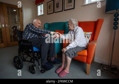 Ein älteres Paar in den Achtzigern, das nach einer mehrwöchigen Trennung aufgrund der Coronavirus-Pandemie, Hampshire, England, wieder in einer Pflege vereint wurde. Stockfoto