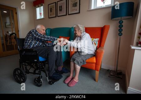 Ein älteres Paar in den Achtzigern, das nach einer mehrwöchigen Trennung aufgrund der Coronavirus-Pandemie, Hampshire, England, wieder in einer Pflege vereint wurde. Stockfoto
