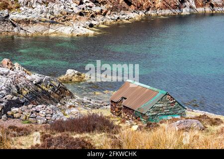 SHIELDAIG WESTER ROSS HIGHLAND SCHOTTLAND BLAUGRÜNES MEER UND EIN KLEINE STEINFISCHERMANNENHÜTTE AM UFER DES OBEREN LOCH TORRIDON Stockfoto