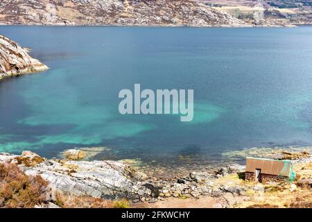 SHIELDAIG WESTER ROSS HIGHLANDS SCHOTTLAND EIN BLAUGRÜNES MEER UND EINE KLEINE STEINFISCHERMANNENHÜTTE AM UFER DES OBEREN LOCH TORRIDON Stockfoto