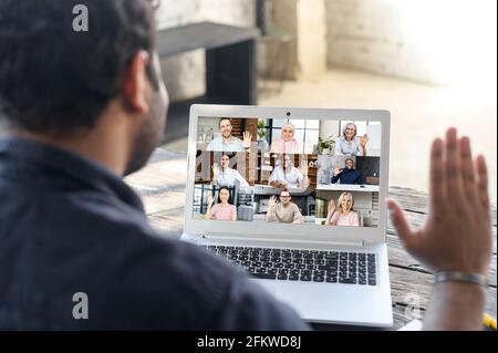 Video-Chat mit Kollegen aus verschiedenen Rassen. Hindu-Typ winkt hoch, begrüßt Gruppe von Menschen auf Online-Video-Meeting, Video verbinden mit Mixed-Race-Kollegen. Rückansicht Mixed-Race-Guy Beteiligte Webinar Stockfoto