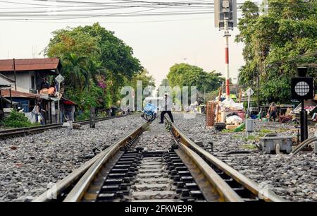 Ein thailändischer Eisverkäufer überquert die Eisenbahnstrecke.Stadtbewohner der Stadt Bangkok, die entlang der Eisenbahnlinie leben. Der Zug der Staatlichen Eisenbahn Thailands (SRT) fährt vom Hauptbahnhof von Bangkok in Hua Lamphong östlich der Hauptstadt und verbindet auf dieser Strecke Chachoengsao, 82 km von Bangkok entfernt. (Foto von Paul Lakatos / SOPA Images/Sipa USA) Stockfoto