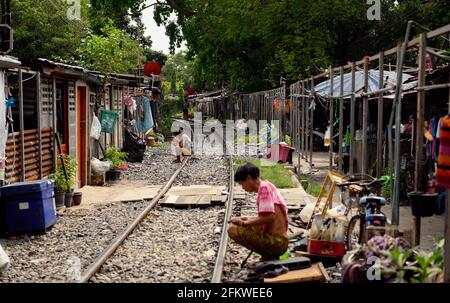 Die Menschen sitzen entlang der Bahngleise.Stadtbewohner der Stadt Bangkok leben entlang der Eisenbahnlinie. Der Zug der Staatlichen Eisenbahn Thailands (SRT) fährt vom Hauptbahnhof von Bangkok in Hua Lamphong östlich der Hauptstadt und verbindet auf dieser Strecke Chachoengsao, 82 km von Bangkok entfernt. Stockfoto