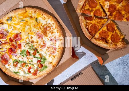 Pepperoni Pizza und Pizza Four Seasons mit Mozzarella-Käse, Schinken, Tomatensauce, Salami, Speck, Pilz, Pfeffer, Gewürze und frisches Basilikumpesto Stockfoto
