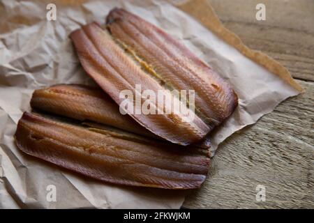 kipper-Schnitzel aus geräuchertem Craster auf einem Holzhintergrund. Kipper sind geräucherte Heringe und sind reich an Fischölen. England GB Stockfoto