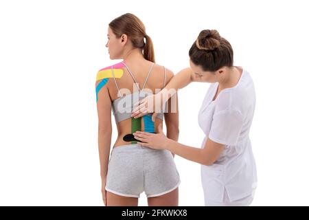 Physiotherapeuten Anwendung kinesio Tape auf der weiblichen Patienten wieder senken. Kinesiologie, Physikalische Therapie, Rehabilitation Konzept. Stockfoto