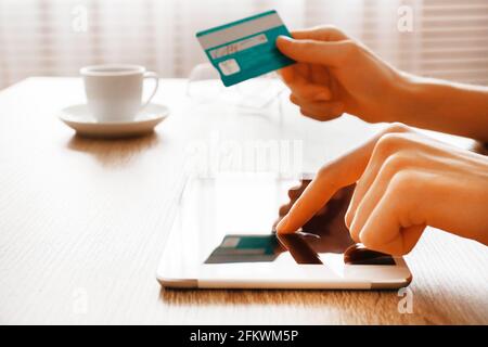Schlanke Frau, die ihre Kreditkarte in den Händen hält und ihr Tablet benutzt. Weibliche kaufen Sachen online, Touchscreen-Gadget. E-Shopping-Konzept. Nahaufnahme, Kopierbereich Stockfoto