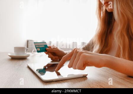 Schlanke Frau, die ihre Kreditkarte in den Händen hält und ihr Tablet benutzt. Weibliche kaufen Sachen online, Touchscreen-Gadget. E-Shopping-Konzept. Nahaufnahme, Kopierbereich Stockfoto