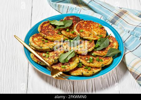 Kichererbsen-Spinat-Pfannkuchen auf einem blauen Teller mit goldener Gabel Auf einem weißen Holztisch Stockfoto