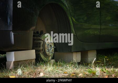 Nahaufnahme des Autos auf Ziegelsteinen draußen. Konzept der gestohlenen Fahrzeugeräder. Auto mit fehlendem Rad. Stockfoto