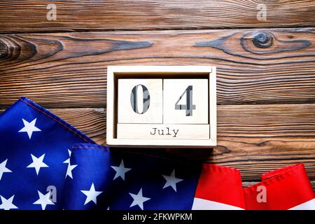 Gekräuselte amerikanische Flagge und Holzwürfelkalender mit Datum des 4. Juli, USA Independence Day auf braunem Holz Vintage-Tisch, Copy Space Hintergrund. US-Patr Stockfoto