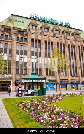 Das historische Gebäude des Kaufhofs an der Kö in Düsseldorf, erbaut 1907 - 1909, mit grünem Vintage-Kiosk und Frühlingswiese. Stockfoto