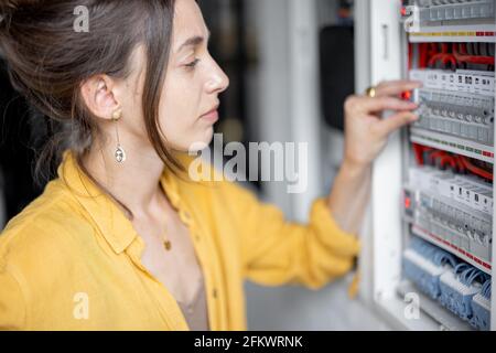 Verwirrt Frau mit Problemen mit Strom zu Hause, spricht am Telefon versuchen, das Problem zu lösen. Konzept der weiblichen Inkompetenz in der häuslichen Elektrizität Stockfoto