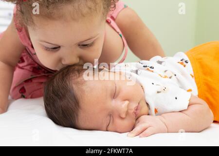 1 Jahr altes Mädchen, das den Kopf ihres Bruders küsst und im Bett schläft. Stockfoto