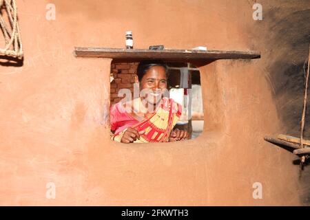 Frau lächelt vom Fenster des Schlammhauses. DESIA KONDHA STAMM. Goipeta Village, Odisha, Indien. Gesichter des ländlichen Indiens Stockfoto