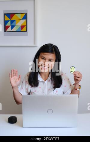 Filipino filipina Asiatische Lehrerin, die vor einem weißen Schreibtisch und silbernem Computer sitzt und online eine Lektion im Internet unterrichtet Stockfoto