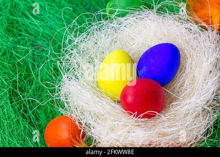 Bunt bemalte Ostereier Dekorationen im Nest auf hellgrünem Hintergrund. Stockfoto