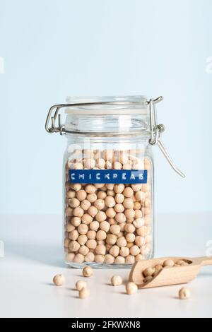 Kichererbsen im Glas mit Holzlöffel auf blauem und weißem Hintergrund. Healthcare Lifestyle und Bio-Food-Konzept. Stockfoto