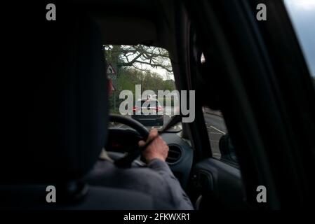 Ein älterer Autofahrer folgt einem lernenden Fahrer, der vom Rücksitz hinter dem Fahrer aus gesehen wird. Stockfoto