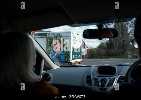 Online einkaufen Morrisons Food van aus der Sicht eines Passagiers in einem Auto, das entlang einer Dorfstraße fährt. Stockfoto