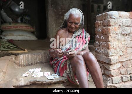 Alte Frau, die vor dem Haus im Dorf Kuanarpal in Cuttack sitzt Bezirk Odisha Spielkarten Stockfoto