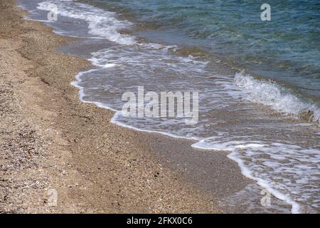 Sandstrand leer, sanfte Wellen Rollen am Ufer. Sand, Kieselsteine, Meerwasser Wellen und Schaum Hintergrund, früh am Morgen. Stockfoto