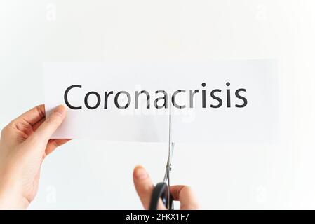 Frau schneidet das Wort Corona Krise mit einer Schere. Stockfoto