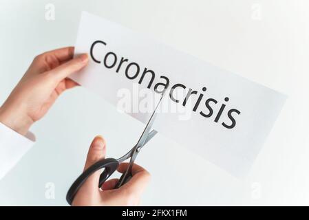 Frau schneidet das Wort Corona Krise mit einer Schere. Stockfoto