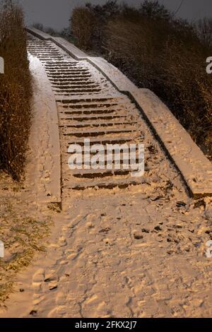 In der Wintersaison verschneite Treppen in einem Park in der Nacht. Stockfoto