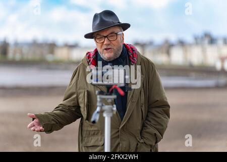 Troon, Schottland, Großbritannien. 4 Mai 2021. George Galloway, Gründer der Pro Union All for Unity Party, wirbt an der Strandpromenade in Troon in Ayrshire. Galloway hielt eine live gestreamte Rede und traf sich mit Unterstützern und Mitgliedern der Öffentlichkeit. Im Wee Hurrie Takeaway Restaurant neben dem Hafen von Troon hatte er ein Mittagessen mit Fisch und Chips. Iain Masterton/Alamy Live News Stockfoto