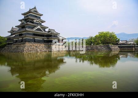 Mensumoto Castle, bekannt als Crow Castle, umgeben von einem grünen Wassergraben, Mensumoto, Japan. Stockfoto