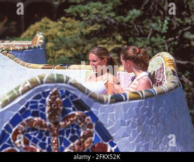 Junge Frauen sitzen auf Keramikbänken, Hauptterrasse, Park Güell, Bezirk Gràcia, Barcelona, Provinz Barcelona, Katalonien, Spanien Stockfoto