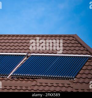 Solarzellenrohr auf braunem Ziegeldach in Nahaufnahme Stockfoto