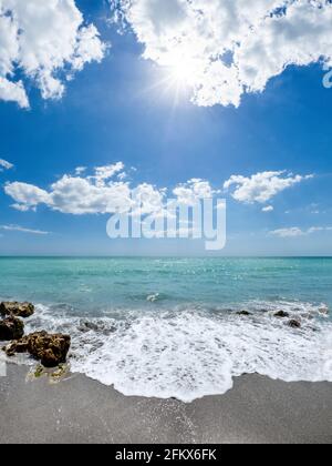 Kleine Wellen brechen unter Felsen am Ufer des Gilf von Mexiko am Caspersen Beach mit blauem Himmel und Weiße Wolken in Venedig, Florida, USA Stockfoto