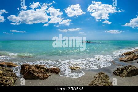 Kleine Wellen brechen unter Felsen am Ufer des Gilf von Mexiko am Caspersen Beach mit blauem Himmel und Weiße Wolken in Venedig, Florida, USA Stockfoto