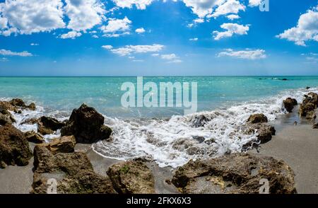 Kleine Wellen brechen unter Felsen am Ufer des Gilf von Mexiko am Caspersen Beach mit blauem Himmel und Weiße Wolken in Venedig, Florida, USA Stockfoto