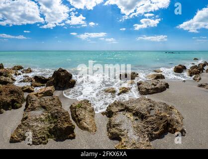 Kleine Wellen brechen unter Felsen am Ufer des Gilf von Mexiko am Caspersen Beach mit blauem Himmel und Weiße Wolken in Venedig, Florida, USA Stockfoto