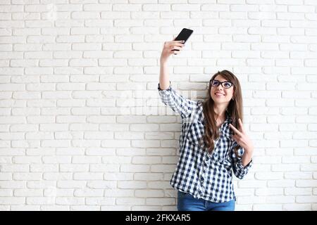 Schöne junge Frau, lange wellige Brünette Haare, im Stil der 90er Jahre gekleidet, Selfie zu machen. Frau trägt Mama Jeans & karierte Hemd machen Bilder von ihr Stockfoto