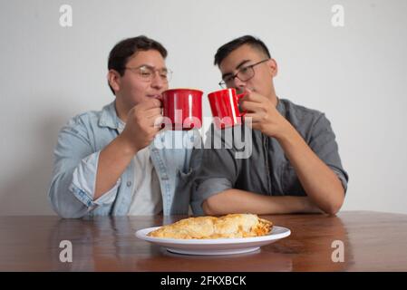 Schwule Paare, die Kaffee haben und ein Molote teilen, leckeres mexikanisches Gericht Stockfoto