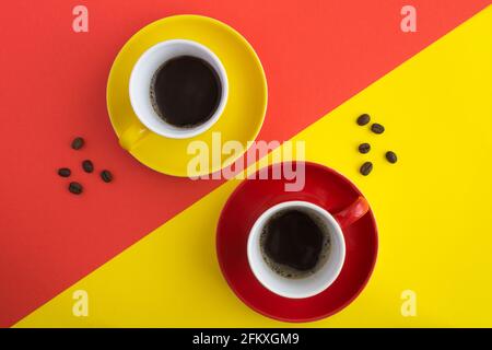 Schwarzer Kaffee in den roten und gelben Tassen auf dem bunten Hintergrund. Speicherplatz kopieren. Draufsicht. Stockfoto
