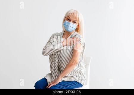 Älterer Bürger Zeigt Geimpften Arm Nach Antiviraler Injektion, White Studio Stockfoto