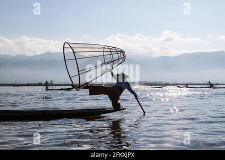 INLE, MYANMAR - 28. NOVEMBER 2016: Einheimische Fischer am Inle See fangen Fisch auf traditionelle Weise mit handgefertigtem Netz. Stockfoto