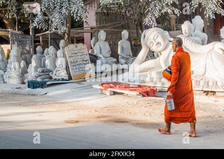 MANDALAY, MYANMAR - 4. DEZEMBER 2016: Buddhistische Mönche wandern entlang Buddha-Statuen, die in lokalen Marmorwerkstätten in Mandalay, Myanmar, geschnitzt wurden Stockfoto