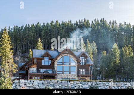 REVELSTOKE, KANADA - 16. MÄRZ 2021: Berghaus aus Holz im Wald zwischen hohen Bäumen. Stockfoto