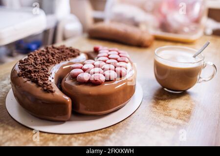 Schöner leckerer Kuchen in der heimischen Küche auf einem hölzernen Tisch und eine duftende Tasse Kaffee Stockfoto