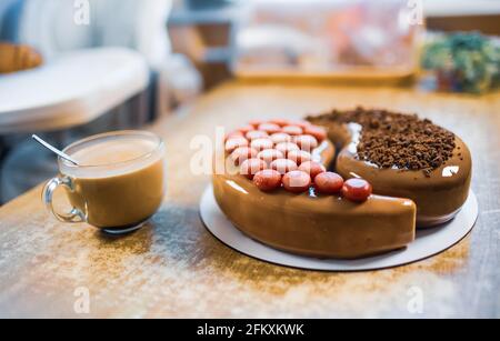 Schöner leckerer Kuchen in der heimischen Küche auf einem hölzernen Tisch und eine duftende Tasse Kaffee Stockfoto