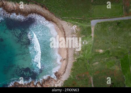 Drone Draufsicht auf einen Wohnmobil auf einem wilden Strand mit grüner Landschaft Stockfoto