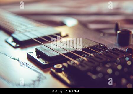 Nahaufnahme einer hölzernen E-Gitarre mit sechs Saiten, selektiver Fokus auf Saiten Stockfoto