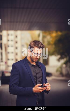 Unternehmer nutzt Handy-Smart. Junger, gutaussehender Geschäftsmann in der Stadt Stockfoto